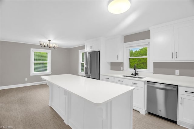 kitchen featuring appliances with stainless steel finishes, a sink, light countertops, a kitchen island, and white cabinetry