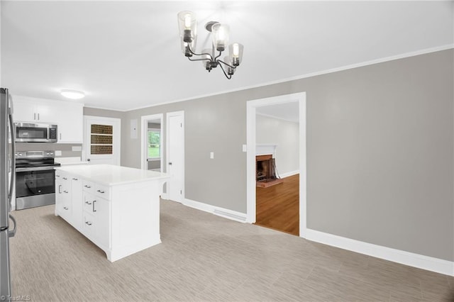 kitchen with appliances with stainless steel finishes, a chandelier, white cabinets, light countertops, and ornamental molding