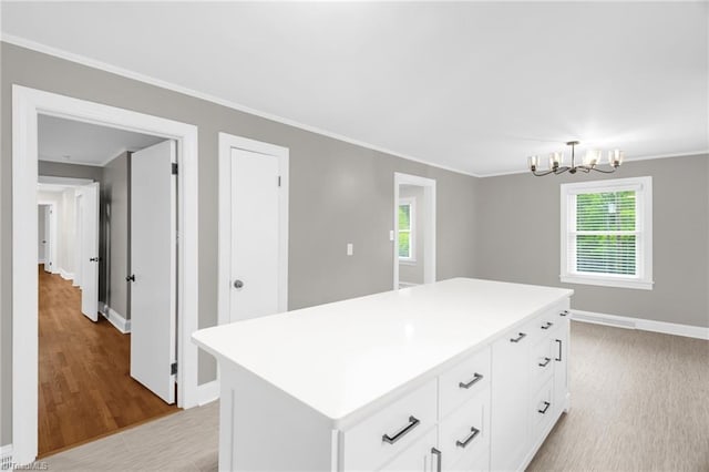 kitchen with baseboards, white cabinetry, ornamental molding, a chandelier, and light countertops