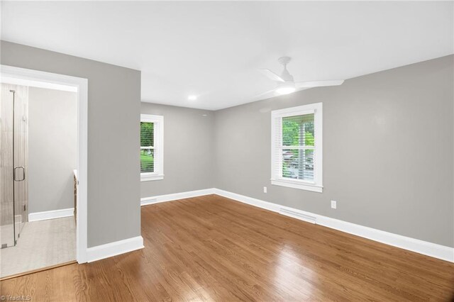 spare room featuring baseboards, wood finished floors, healthy amount of natural light, and a ceiling fan