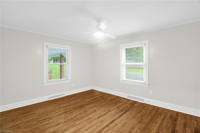 unfurnished room with crown molding, wood finished floors, a ceiling fan, and baseboards