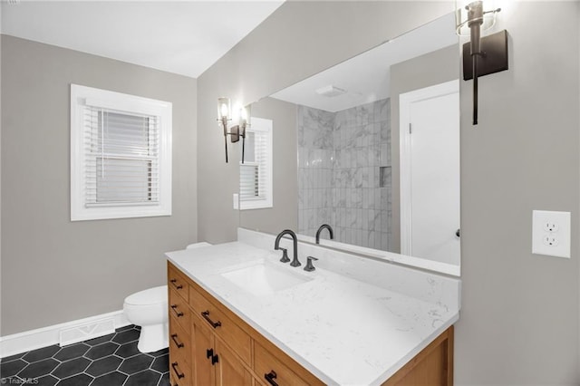 full bathroom with baseboards, vanity, toilet, tile patterned floors, and tiled shower