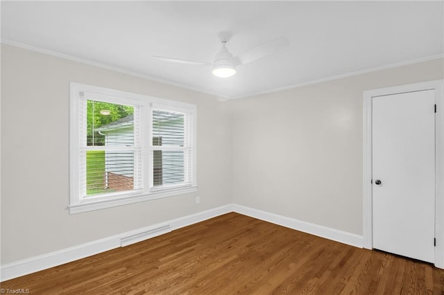 spare room featuring wood finished floors, ornamental molding, baseboards, and a ceiling fan
