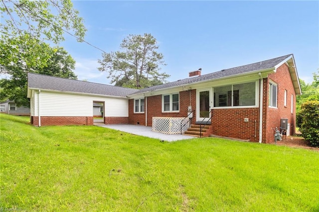 rear view of house featuring a lawn, a chimney, a patio area, and brick siding