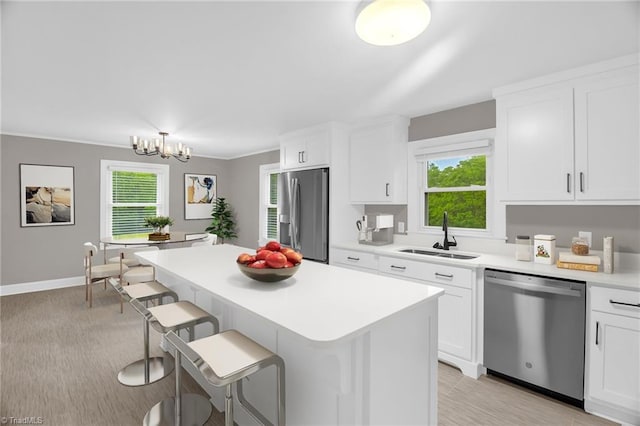 kitchen featuring stainless steel appliances, a sink, light countertops, a breakfast bar, and a kitchen island