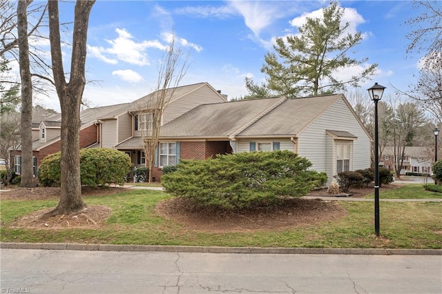 view of front facade with brick siding and a front yard