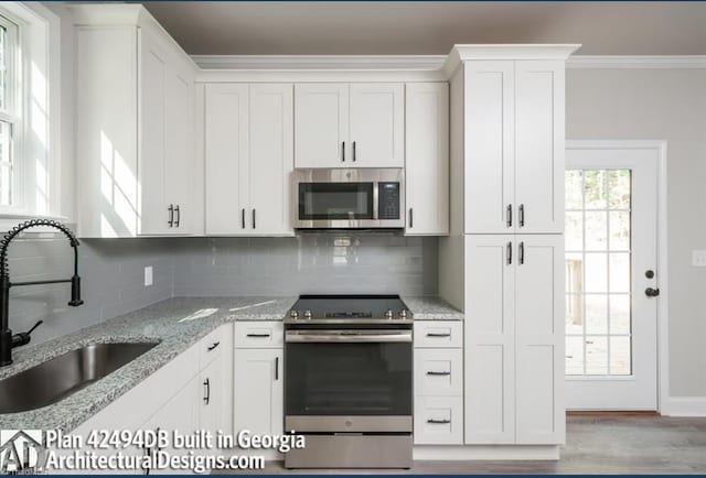 kitchen featuring stainless steel appliances, decorative backsplash, white cabinets, and sink