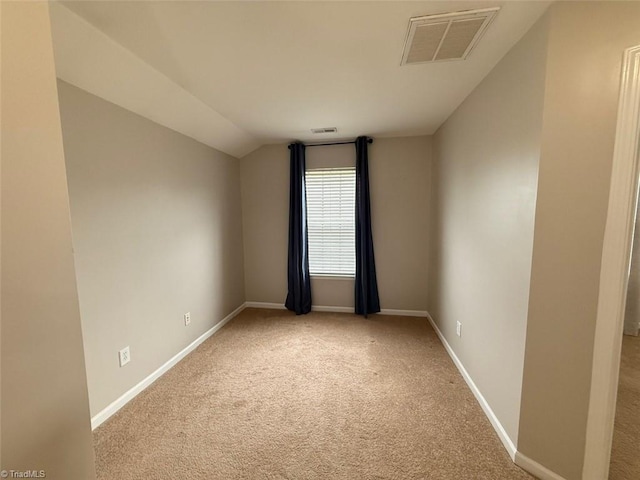 spare room featuring light carpet and lofted ceiling