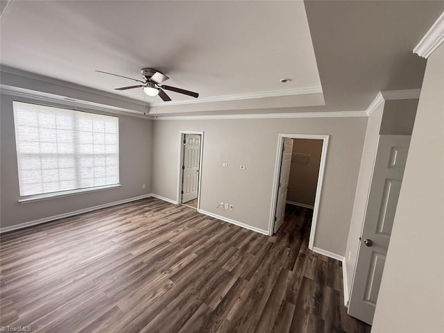 empty room featuring a tray ceiling, ceiling fan, dark wood finished floors, and crown molding