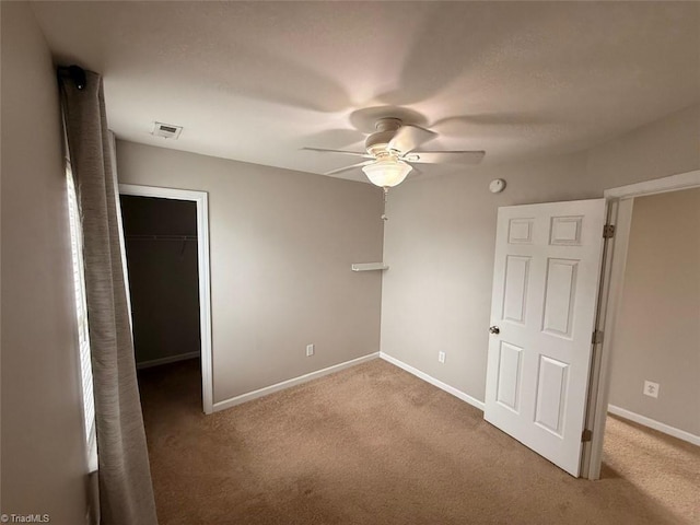 unfurnished bedroom featuring carpet floors, a spacious closet, ceiling fan, and a closet