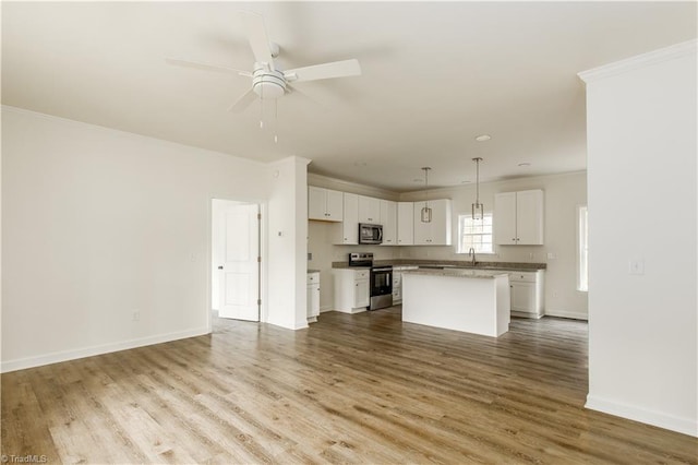 kitchen with appliances with stainless steel finishes, hardwood / wood-style floors, a center island, white cabinetry, and hanging light fixtures