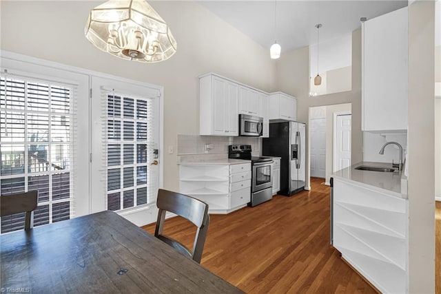 kitchen featuring wood finished floors, a sink, white cabinets, appliances with stainless steel finishes, and tasteful backsplash