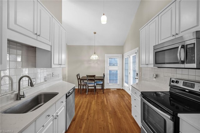 kitchen featuring lofted ceiling, a sink, stainless steel appliances, light countertops, and white cabinets