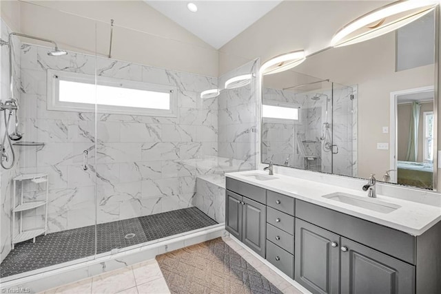 ensuite bathroom featuring a marble finish shower, a healthy amount of sunlight, lofted ceiling, and a sink