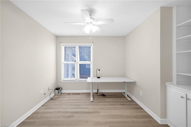 unfurnished office with a ceiling fan, baseboards, and light wood finished floors