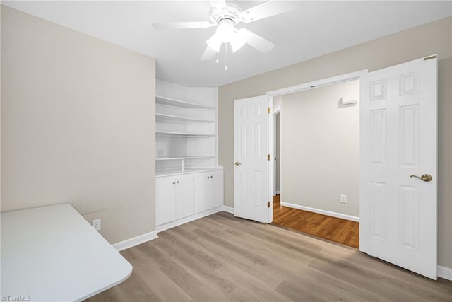 unfurnished office featuring baseboards, light wood-type flooring, and ceiling fan