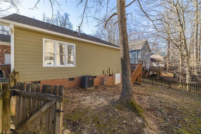 view of side of home with crawl space, central AC, a shingled roof, and fence