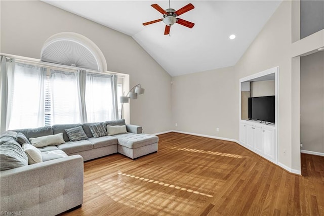 living area featuring high vaulted ceiling, baseboards, ceiling fan, and wood finished floors