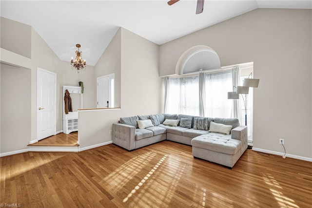 living room featuring baseboards, high vaulted ceiling, wood finished floors, and ceiling fan with notable chandelier