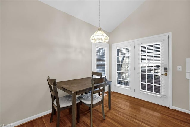 dining room with baseboards, wood finished floors, and vaulted ceiling