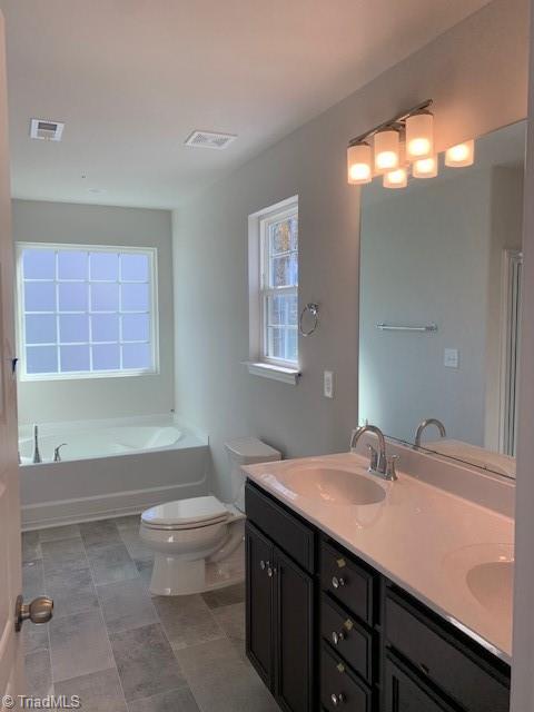 bathroom with vanity, toilet, and a tub