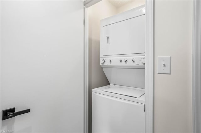 clothes washing area featuring stacked washer and clothes dryer