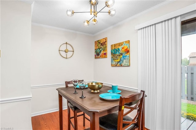 dining area with ornamental molding, wood-type flooring, and a notable chandelier