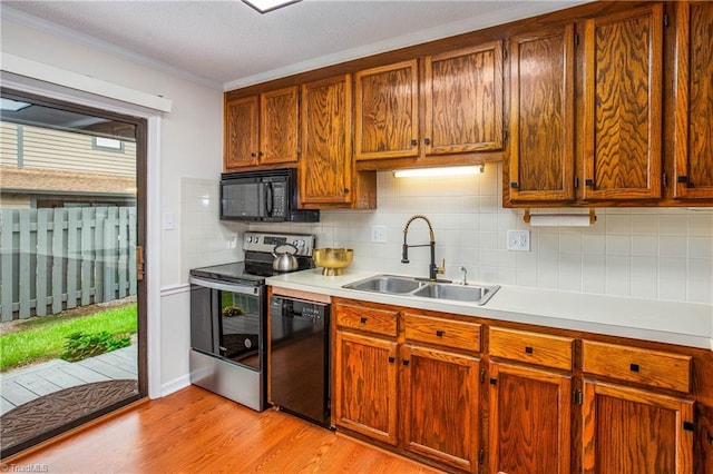 kitchen with sink, light hardwood / wood-style flooring, decorative backsplash, black appliances, and ornamental molding