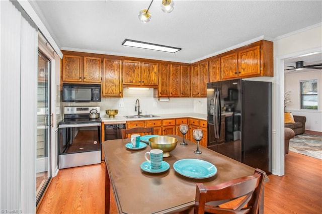 kitchen with tasteful backsplash, black appliances, light hardwood / wood-style flooring, ornamental molding, and sink