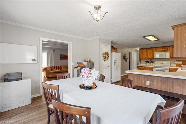 dining space featuring hardwood / wood-style flooring, ornamental molding, and a textured ceiling