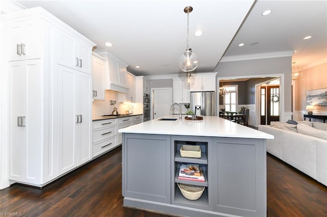 kitchen featuring sink, hanging light fixtures, a kitchen island with sink, stainless steel appliances, and white cabinets