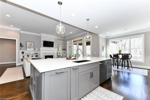 kitchen featuring pendant lighting, sink, a kitchen island with sink, gray cabinetry, and dark hardwood / wood-style flooring