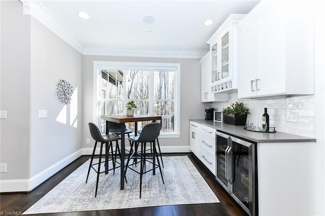 dining space with dark wood-type flooring, crown molding, wine cooler, and bar area