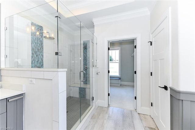 bathroom with wood-type flooring, a shower with door, crown molding, and vanity