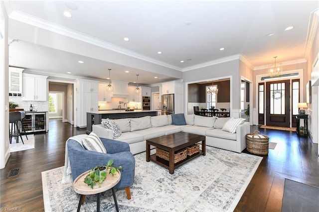 living room with dark wood-type flooring, crown molding, and a chandelier