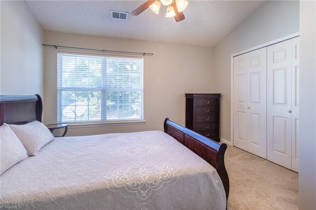 carpeted bedroom featuring lofted ceiling, a textured ceiling, a closet, and ceiling fan