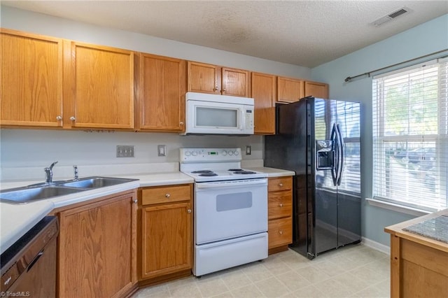 kitchen with sink, a textured ceiling, and white appliances