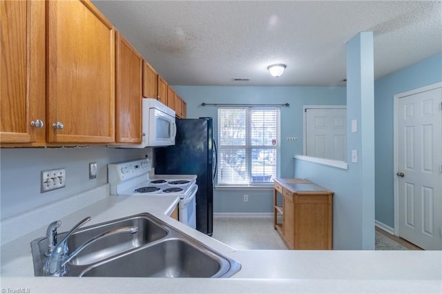 kitchen with sink, a textured ceiling, white appliances, and light tile patterned floors