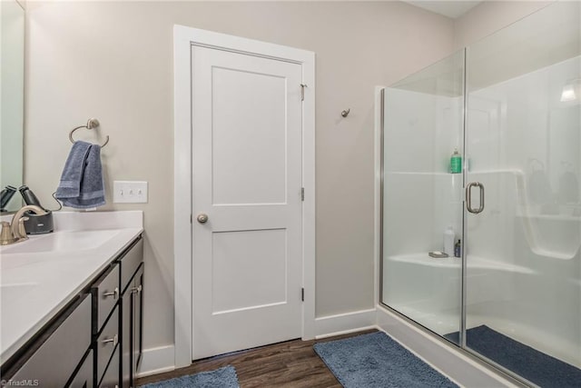 bathroom with a shower with shower door, hardwood / wood-style floors, and vanity