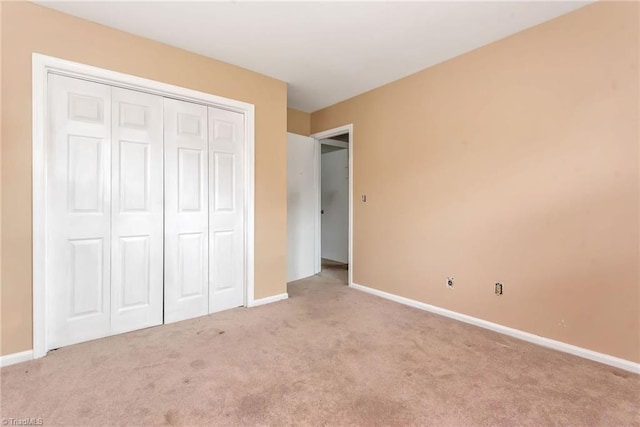 unfurnished bedroom featuring light colored carpet and a closet