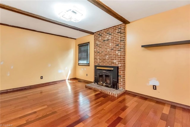 unfurnished living room with hardwood / wood-style flooring, a brick fireplace, and beam ceiling