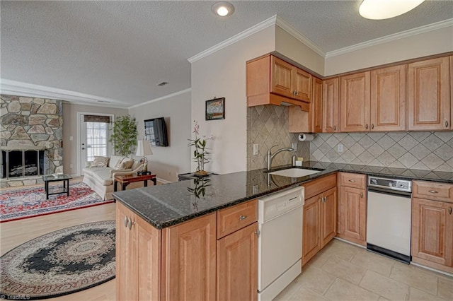 kitchen featuring a stone fireplace, sink, dishwasher, dark stone countertops, and decorative backsplash