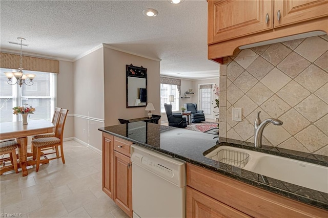 kitchen featuring dark stone countertops, sink, dishwasher, hanging light fixtures, and ornamental molding