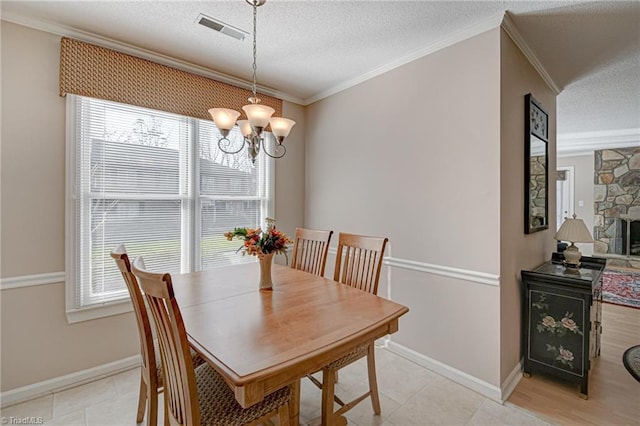 dining room with an inviting chandelier, crown molding, a textured ceiling, and a fireplace