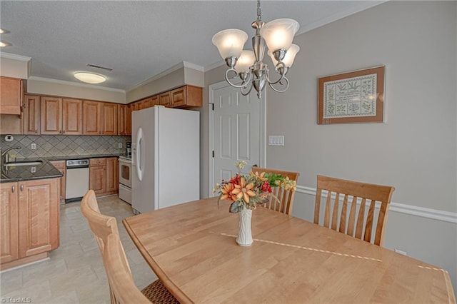 dining space with a textured ceiling, a chandelier, sink, and ornamental molding