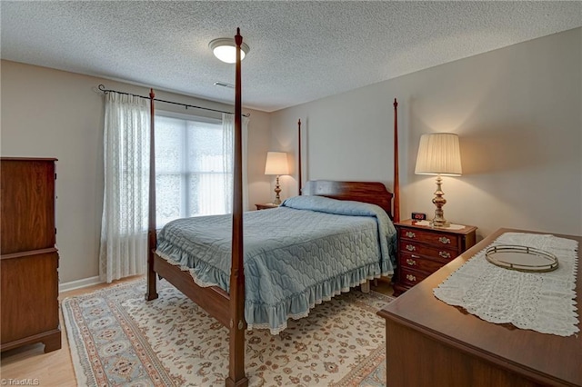 bedroom with light wood-type flooring and a textured ceiling