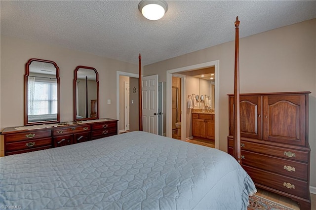 bedroom featuring ensuite bath and a textured ceiling