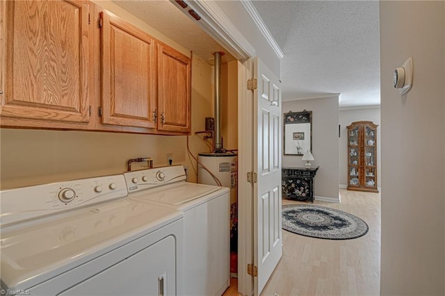 laundry area with light wood-type flooring, crown molding, a textured ceiling, and cabinets