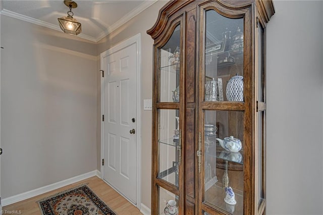 entryway with light wood-type flooring and crown molding