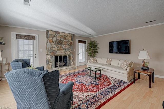 living room featuring hardwood / wood-style flooring, ornamental molding, a textured ceiling, and a fireplace